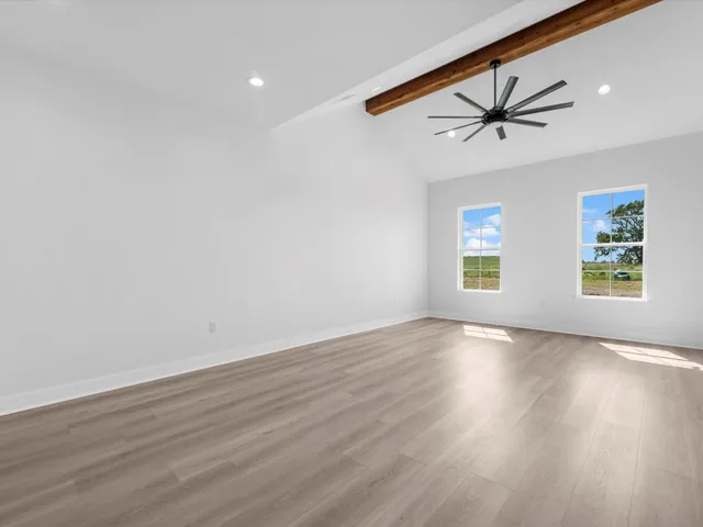 an empty room with wooden floor windows and ceiling fan