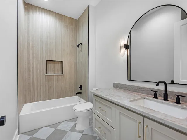 a bathroom with a granite countertop sink a toilet and bathtub