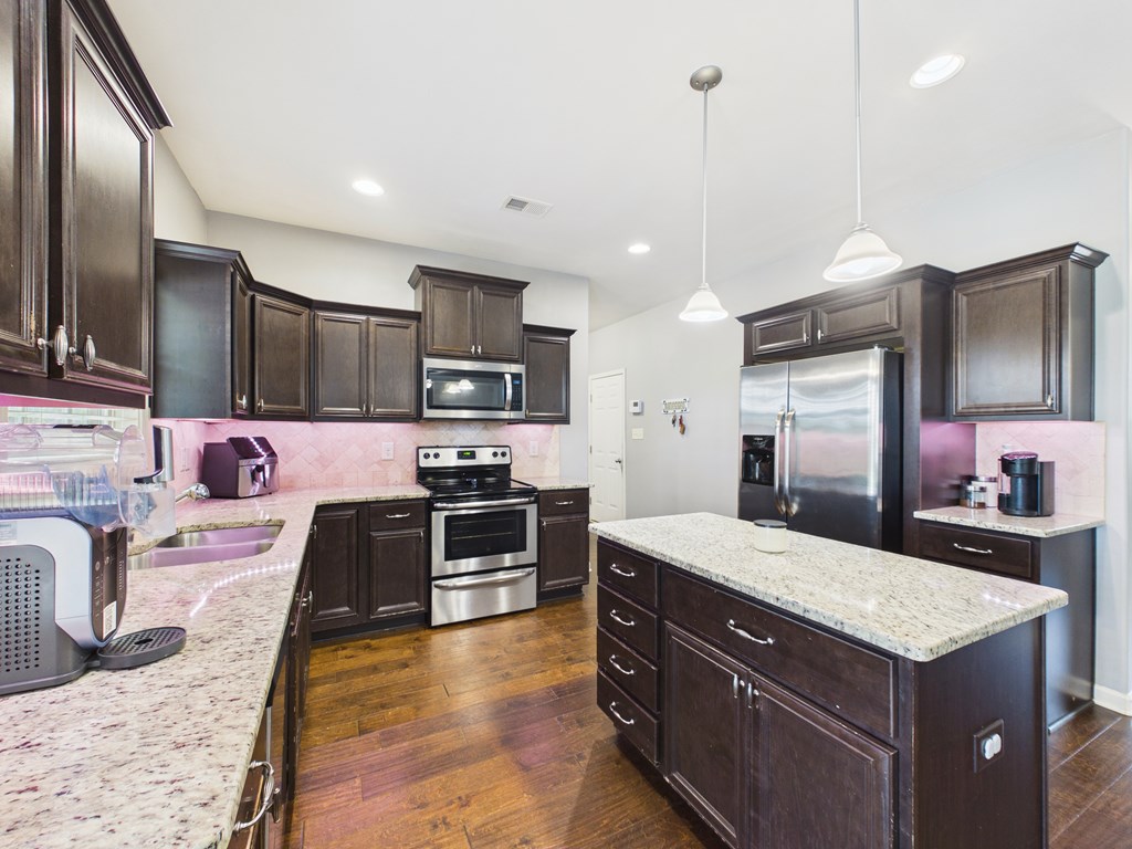 783 Sweetbay Parkway Hamilton, GA 31811 - Photo 13 of 46 a kitchen with kitchen island granite countertop a stove oven and refrigerator