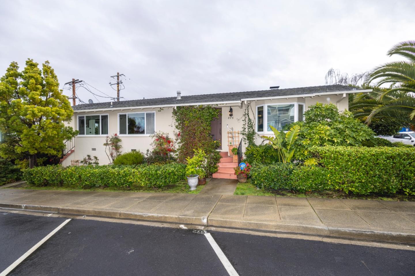 a front view of a house with a yard and potted plants