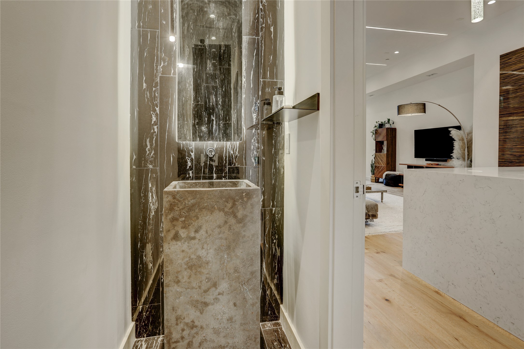 1807 Indiana Street Houston, TX 77006 - Photo 17 of 35 Powder Room: Modern second-floor half bath located just off the kitchen, showcasing a dramatic full-height dark marble accent wall, a backlit floating mirror, and a statement-making monolithic stone pedestal sink.