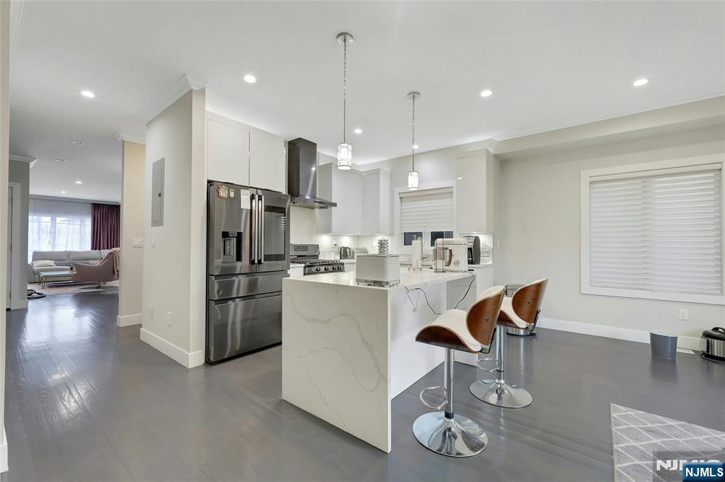 229 6th Street, Unit A Fairview, NJ 07022 - Photo 11 of 35 a kitchen with stainless steel appliances granite countertop a refrigerator a oven a sink a dining table and chairs with wooden floor
