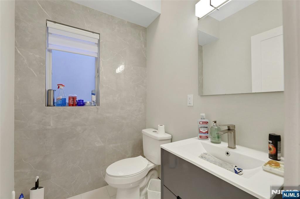 229 6th Street, Unit A Fairview, NJ 07022 - Photo 9 of 35 a bathroom with a sink mirror and toilet