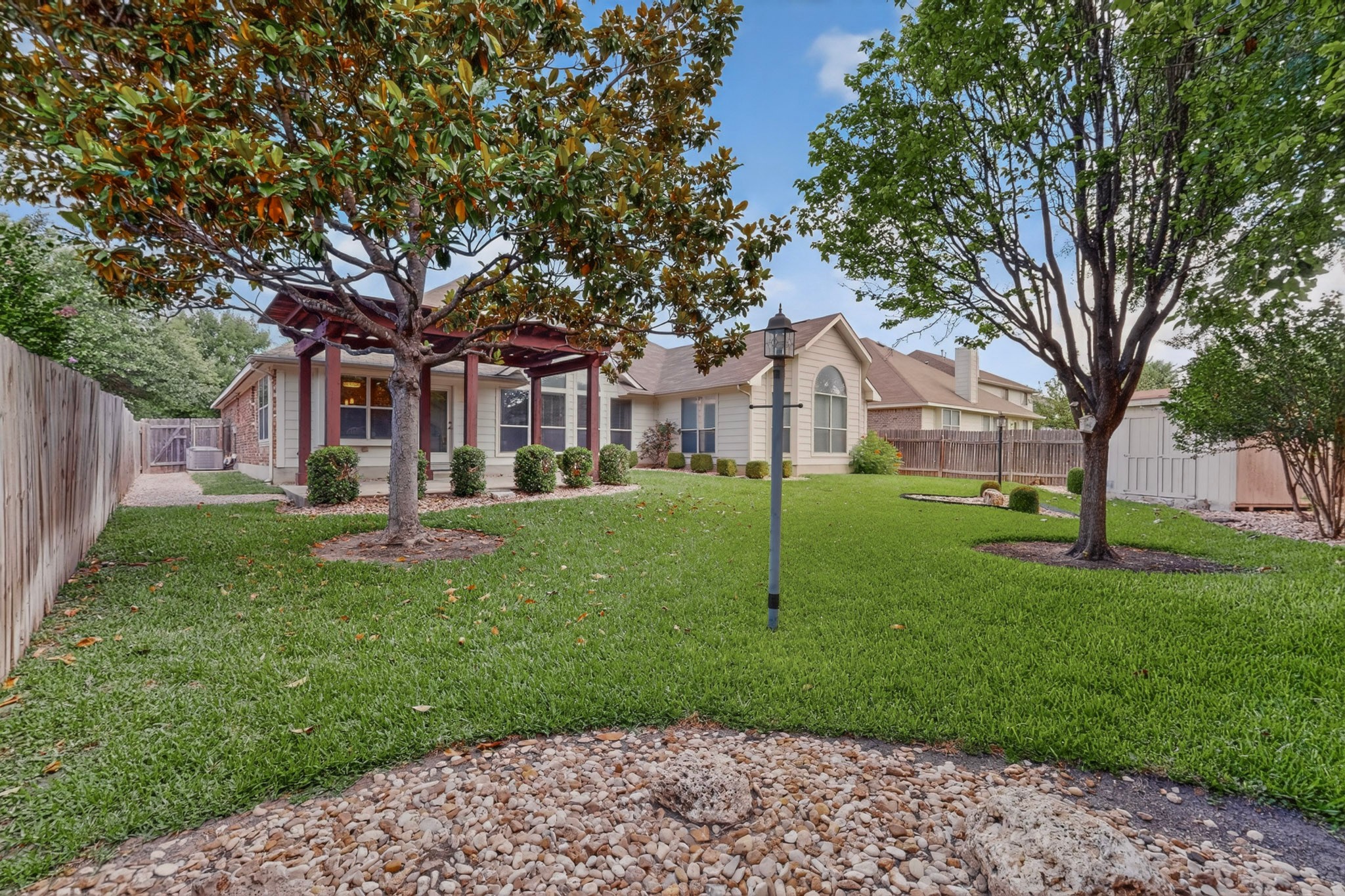905 Victoria Ridge Drive Pflugerville, TX 78660 - Photo 25 of 32 A verdant lawn graces this property, featuring mature trees and a charming pergola leading to the back of the house.