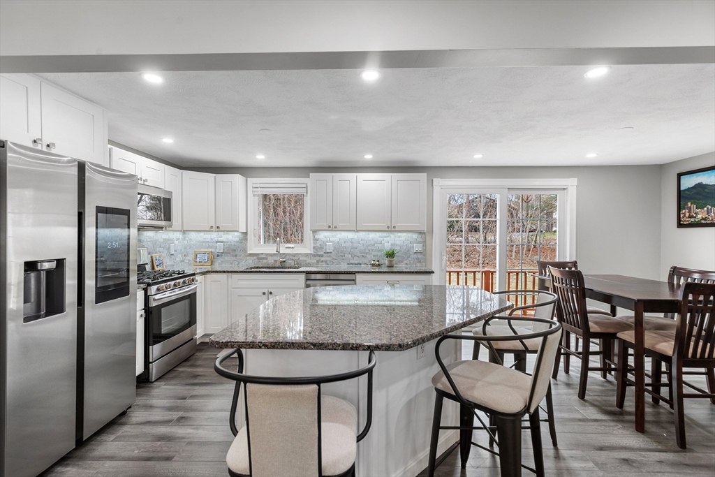16 Bear Hill Road Billerica, MA 01821 - Photo 3 of 28 a kitchen with granite countertop a table chairs microwave and refrigerator