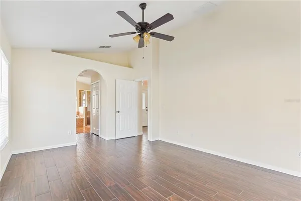a view of an empty room with wooden floor and a window