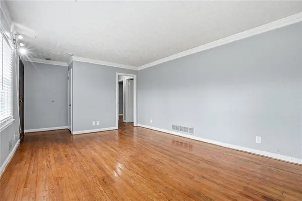 a view of an empty room with wooden floor and a window