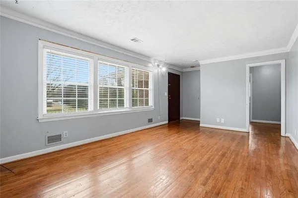 a view of an empty room with wooden floor and a window