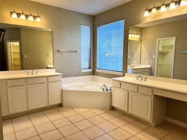 a spacious bathroom with a double vanity sink mirror and bathtub