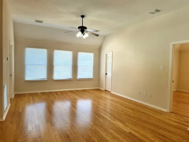 a view of an empty room with wooden floor and a window