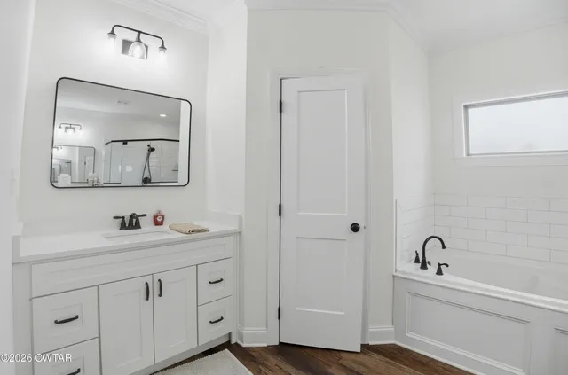 a bathroom with a double vanity sink mirror and bathtub