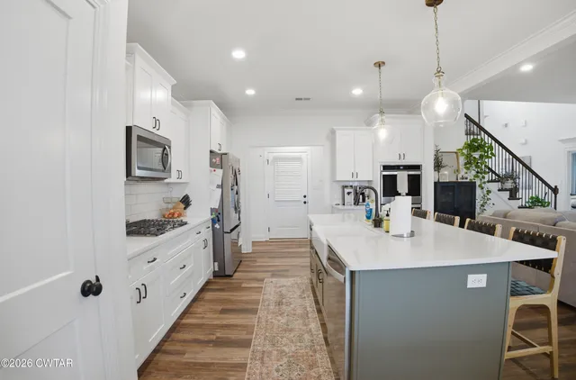 a kitchen with stainless steel appliances kitchen island granite countertop a sink and a refrigerator