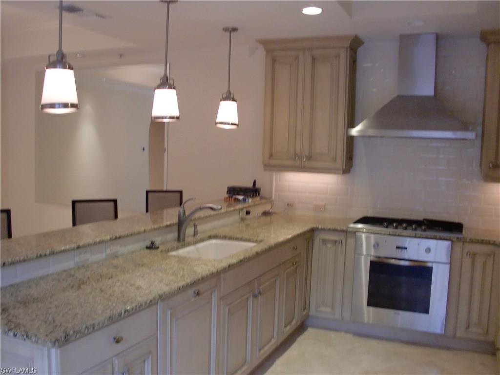 435 3rd Avenue South, Unit 3 Naples, FL 34102 - Photo 5 of 12 a kitchen with stainless steel appliances granite countertop a sink a stove and a wooden floors