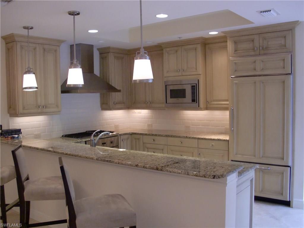 435 3rd Avenue South, Unit 3 Naples, FL 34102 - Photo 6 of 12 a kitchen with a sink a refrigerator a stove and a wooden cabinets