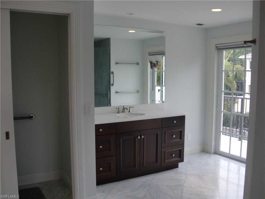 435 3rd Avenue South, Unit 3 Naples, FL 34102 - Photo 8 of 12 a spacious bathroom with a double vanity sink a mirror and a bathtub