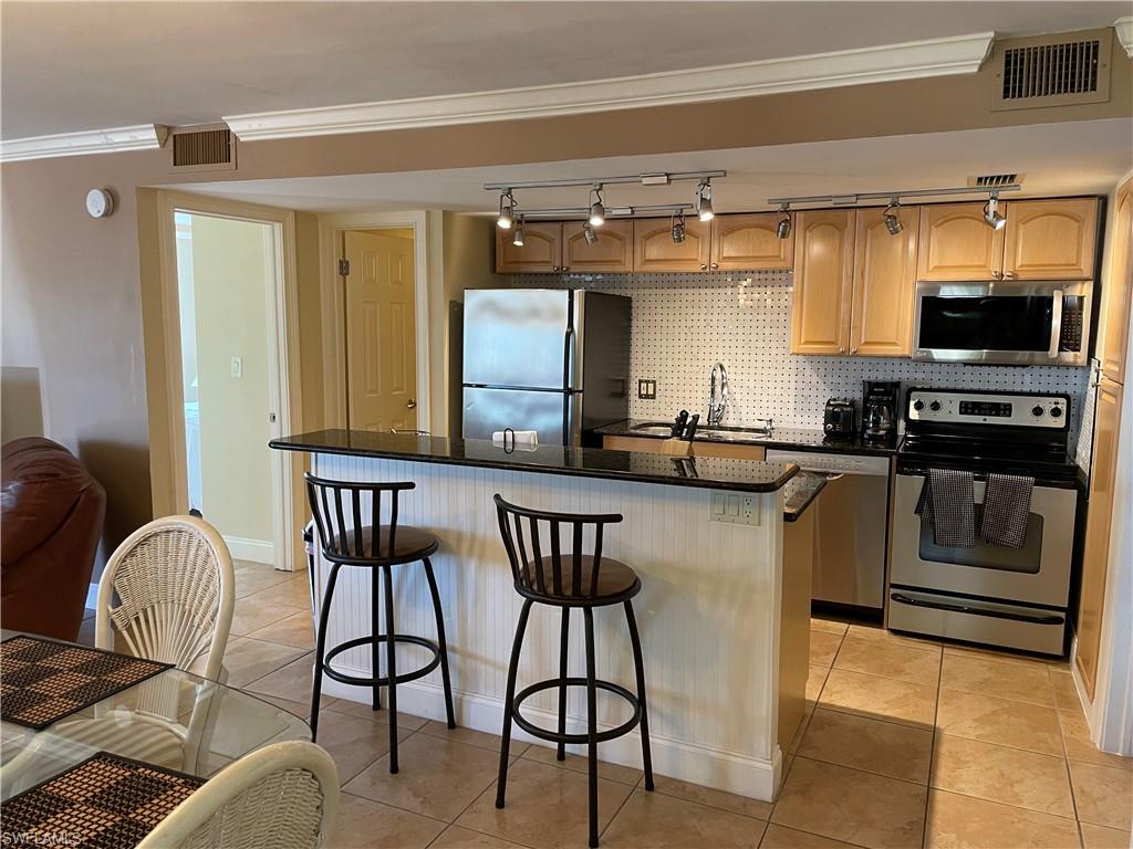 200 Palm Drive, Unit 7 Naples, FL 34112 - Photo 1 of 21 a kitchen with granite countertop a table chairs stove a sink and dishwasher