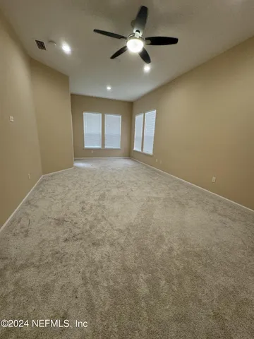 en empty room with windows and ceiling fan