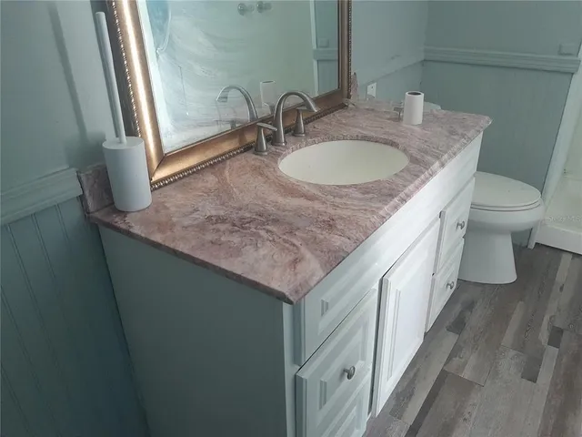 a bathroom with a granite countertop sink and a toilet