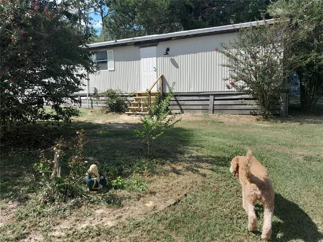 a view of backyard with wooden fence and large trees