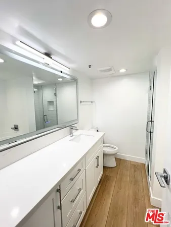 a spacious bathroom with a granite countertop sink mirror vanity and toilet