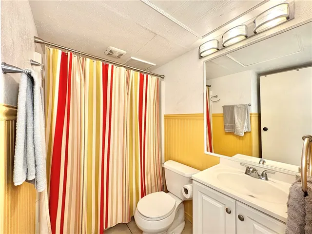 a bathroom with a sink a toilet and shower curtain