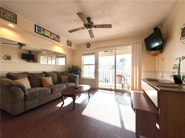 a living room with furniture a ceiling fan and a flat screen tv