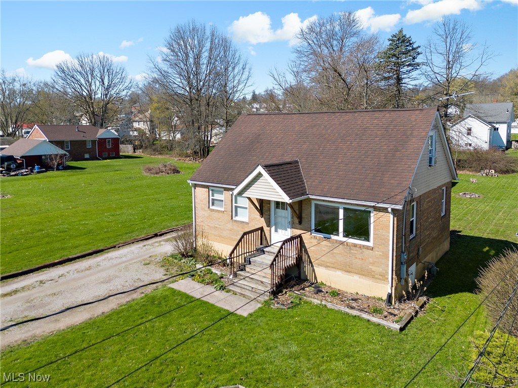 View of front of house featuring brick siding, a shingled roof, and a front yard