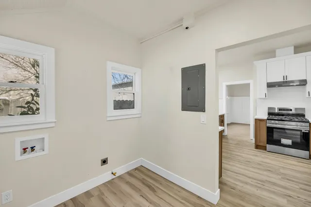 a view of a hallway with wooden floor and a bathroom