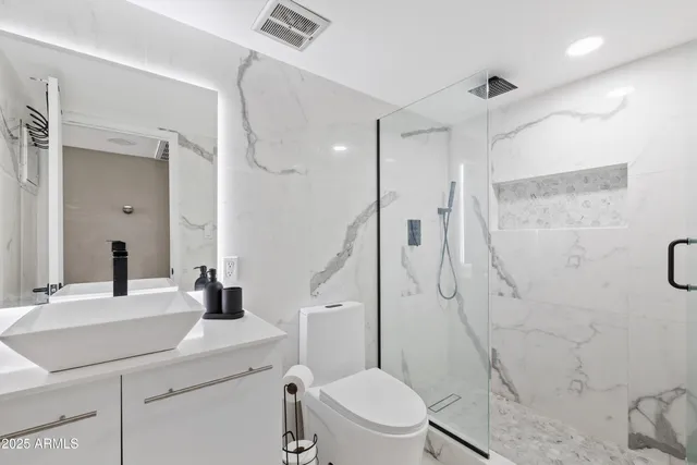 a bathroom with a sink a toilet a mirror and shower