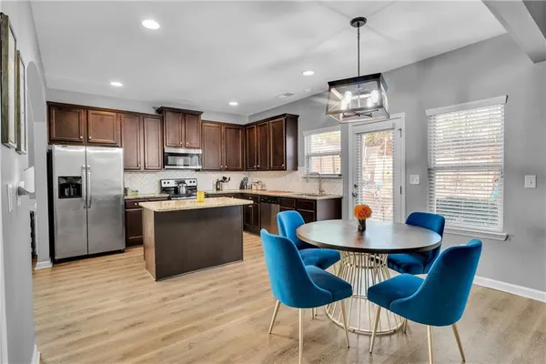 a kitchen with stainless steel appliances granite countertop a sink a stove a kitchen island with a dining table and chairs