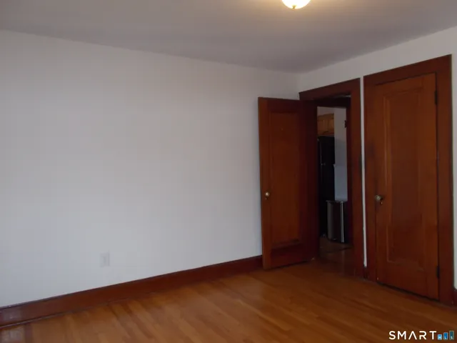 a view of an empty room with wooden floor and closet
