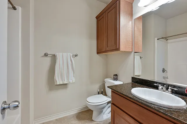 a bathroom with a granite countertop sink toilet and a mirror