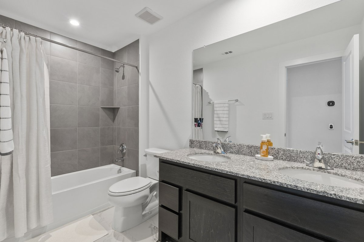 1904 Varese Path Leander, TX 78641 - Photo 26 of 40 a bathroom with a granite countertop sink toilet mirror and shower