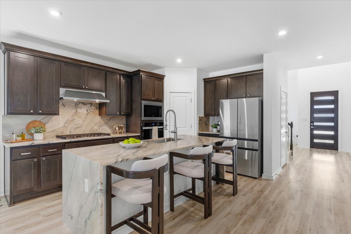 1904 Varese Path Leander, TX 78641 - Photo 8 of 40 a kitchen with stainless steel appliances a dining table chairs refrigerator and sink