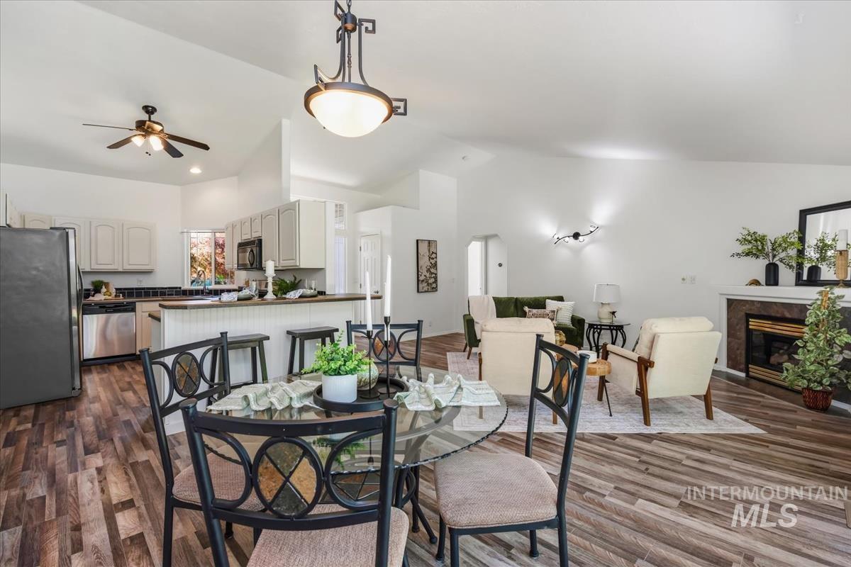 802 North Echohawk Way Eagle, ID 83616 - Photo 15 of 30 Open-concept living space featuring wood-finish flooring, vaulted ceilings, and a fireplace with a stone surround