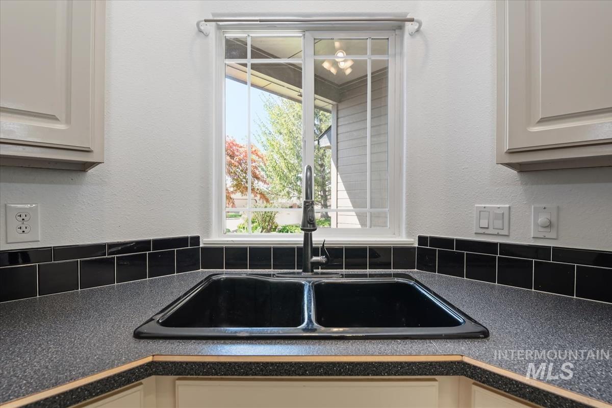 802 North Echohawk Way Eagle, ID 83616 - Photo 17 of 30 Kitchen sink with a black double basin, a gooseneck faucet, and a large window