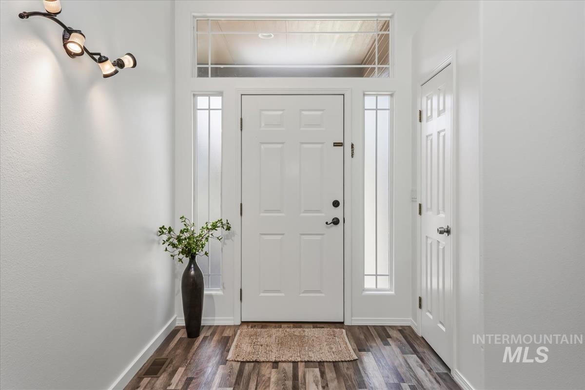 802 North Echohawk Way Eagle, ID 83616 - Photo 18 of 30 Entryway featuring a paneled door with glass sidelights and transom, wood-finish flooring, and white walls