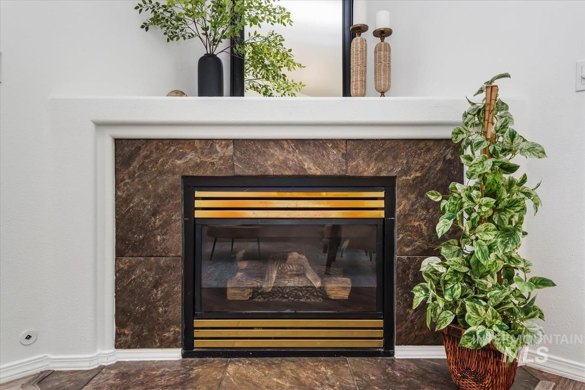 802 North Echohawk Way Eagle, ID 83616 - Photo 20 of 30 Fireplace with a stone surround and hearth, featuring a metal firebox with brass-toned accents and a white mantel