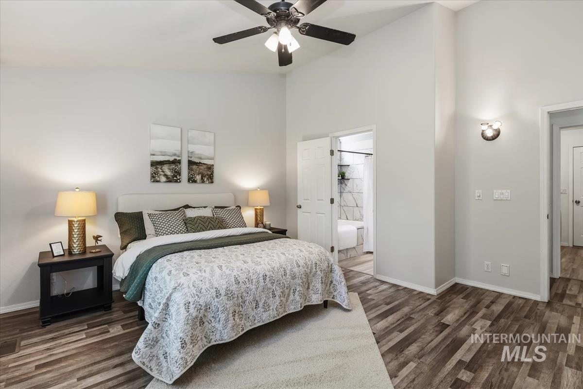 802 North Echohawk Way Eagle, ID 83616 - Photo 6 of 30 Spacious bedroom featuring vaulted ceilings, wood-finish flooring, a contemporary ceiling fan, a wall-mounted sconce, and an en-suite bathroom with a tiled shower