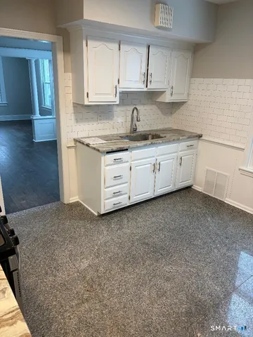 a kitchen with granite countertop white cabinets and white stainless steel appliances