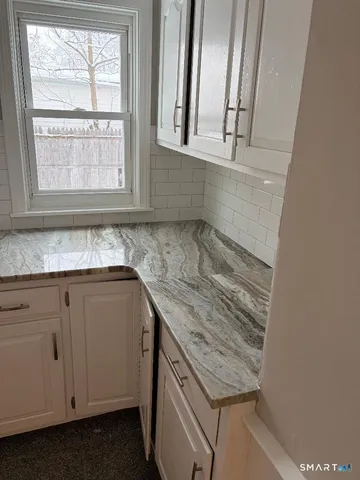 a sink with granite countertop cabinets and window