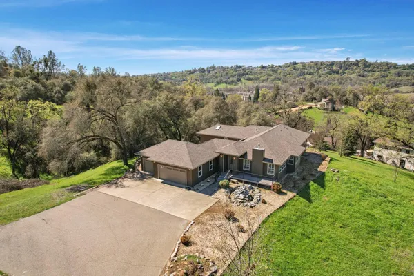 an aerial view of a house with garden space and trees all around