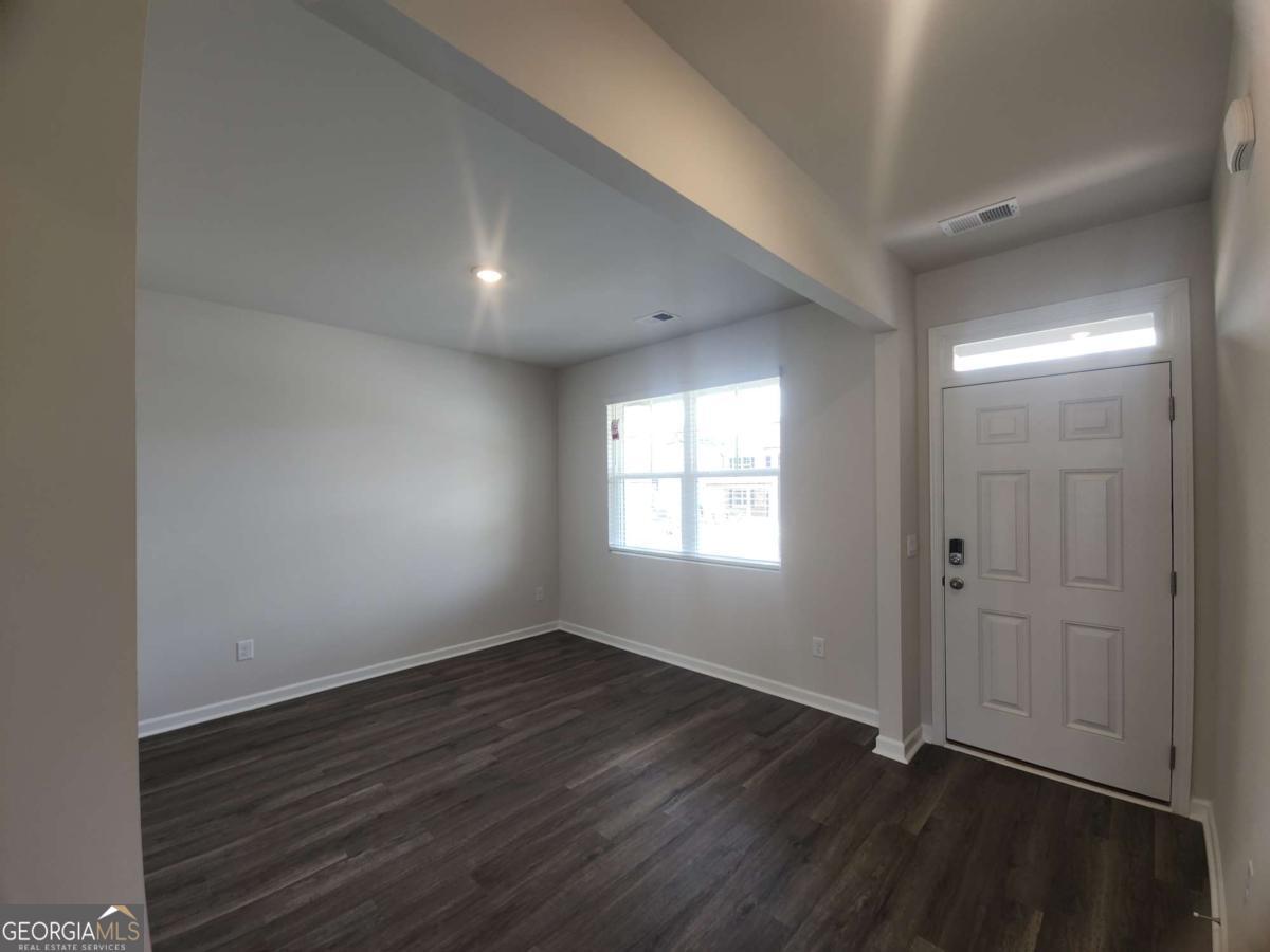 146 Aster Avenue Locust Grove, GA 30248 - Photo 5 of 25 a view of an empty room with wooden floor and a window