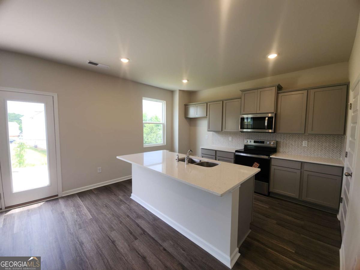 146 Aster Avenue Locust Grove, GA 30248 - Photo 9 of 25 a kitchen with stainless steel appliances granite countertop a sink stove and refrigerator
