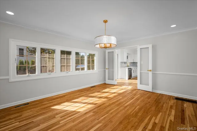 a view of empty room with wooden floor and chandelier