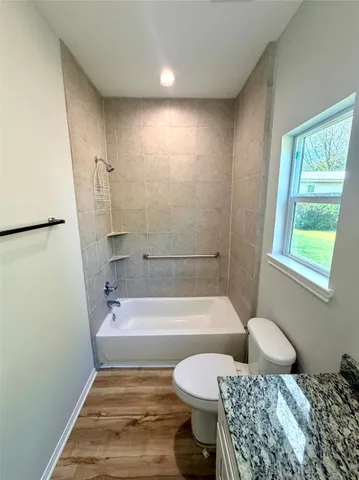 an empty room with wooden floor and a ceiling fan