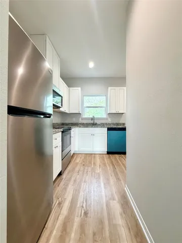 a kitchen with granite countertop white cabinets and a stove