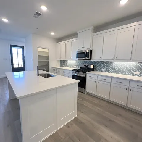a kitchen with white cabinets sink and stove