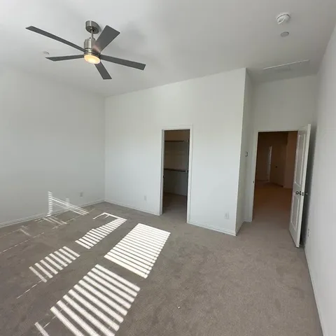 a view of a bedroom with a bed and a ceiling fan