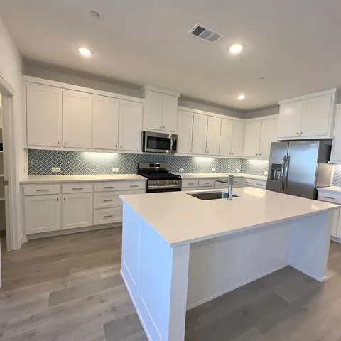 a kitchen with a sink a stove a refrigerator a center island and cabinets